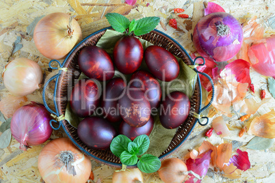 Easter eggs in wicker basket and onion, top view