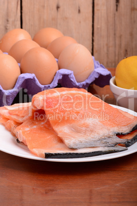 fresh salmon fillet close up on white plate. eggs and lemon