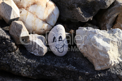 Funny face is drawn on a round pebble