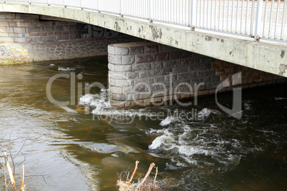 The rapid flow of the river under the bridge