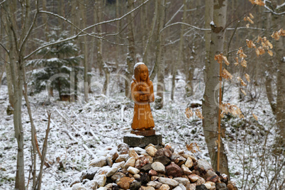 wooden figurine on stones in the forest