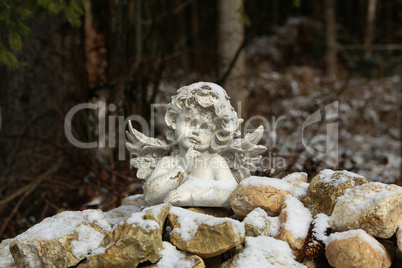 figurine: white angel on stones in the forest