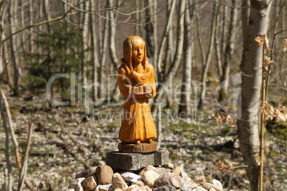 wooden figurine on stones in the forest