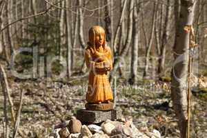 wooden figurine on stones in the forest