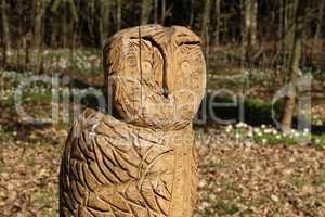 The figure of an owl, planed from a tree, stands in the forest