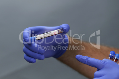 Coronavirus testing - a hand holds test tubes containing patient blood samples with results for coronavirus