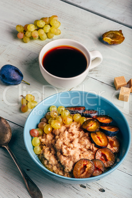 Porridge with plum, grapes and cup of coffee