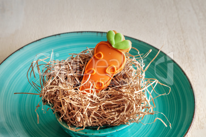 Orange carrot sugar cookie in an Easter basket nest