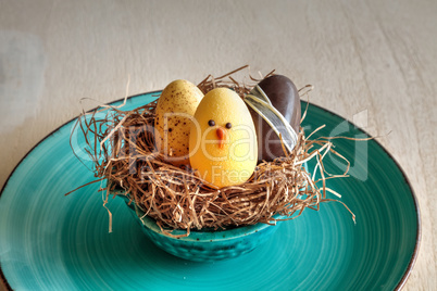 Three chocolate eggs of all colors in an Easter basket nest