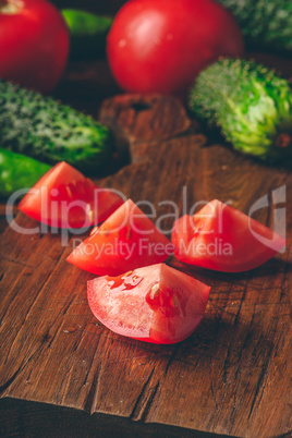 Sliced tomatoes on cutting board and cucumbers with chili pepper