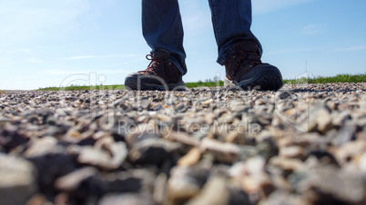 Legs of a man in sneakers stand on a gravel road