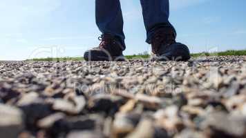 Legs of a man in sneakers stand on a gravel road