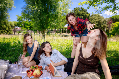 Picnic at the park, four friends play and have fun while eating