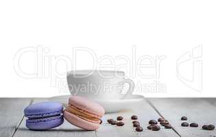 Two macaroons with cup and coffee grains