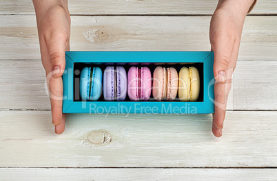 Female hands holding box with macaroons