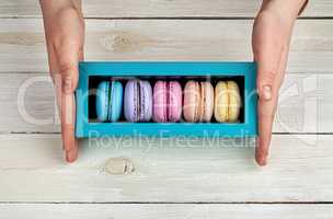 Female hands holding box with macaroons