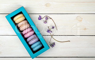 Macaroons in gift box next to violet