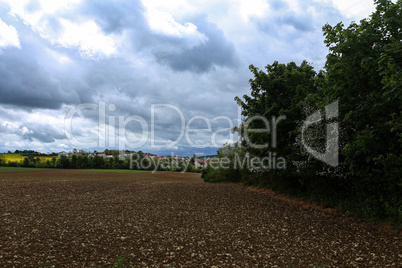 Plowed field with new buildings away in cloudy weather