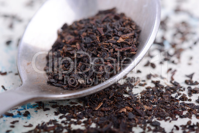 Black tea in a spoon on a white background. Close up shot