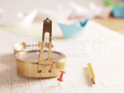 Close up of a compass and location marking with a red pin on sea