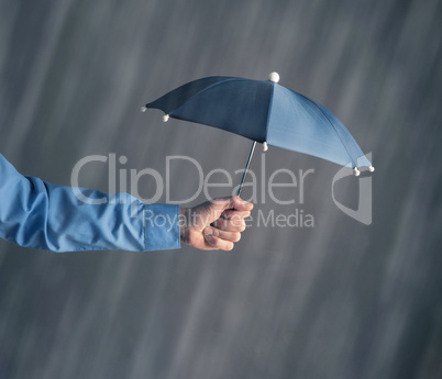 Hand of a businessman with an umbrella in rain