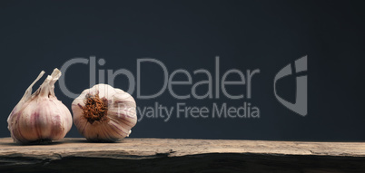 Two bulbs of garlic on a rustic kitchen table