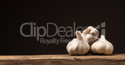 Four bulbs of garlic on a rustic kitchen table