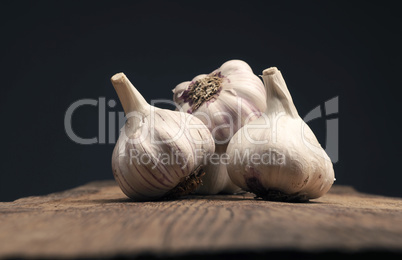 Four bulbs of garlic on a rustic kitchen table