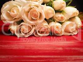Bouquet of white roses on a red wooden table