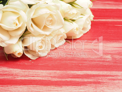 Bouquet of white roses on a red wooden table