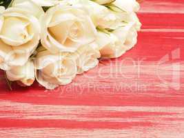 Bouquet of white roses on a red wooden table