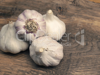 Four bulbs of garlic on a rustic kitchen table