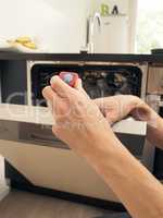 A middle-aged man equips a dishwasher with a cleaning tab