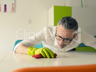 Middle-aged man thoroughly cleans a white dining room table