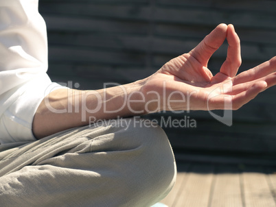 Man relaxes while meditating on a wooden terrace