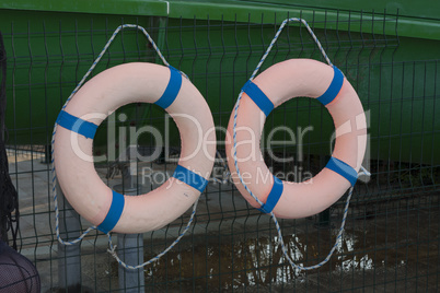 Two orange lifebuoys on hanging on a wooden wall of a boat station photo