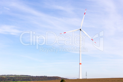 A windmill on a field with blue sky
