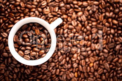 White cup with coffee beans on a background of coffee beans