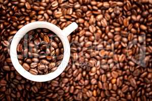 White cup with coffee beans on a background of coffee beans