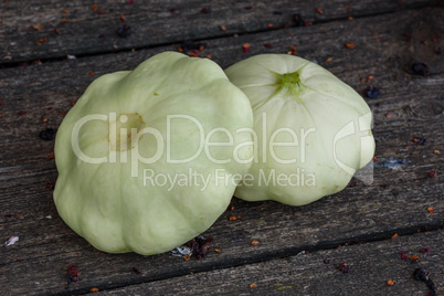 Two pattypan squash lie on the old wooden table in the garden