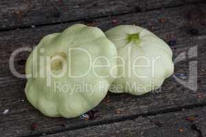 Two pattypan squash lie on the old wooden table in the garden