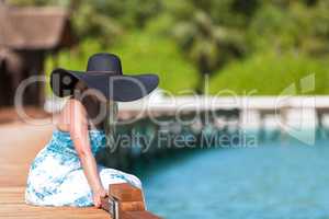 Maldives, a young woman sitting on a bridge in a black hat