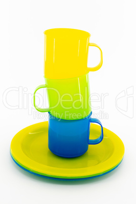 Three colored mugs and three colored saucers on a white backgrou