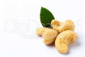 Cashew nuts with a green leaf on white background