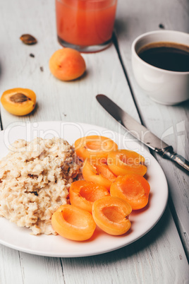 Porridge with apricot, coffee, glass of juice and croissant