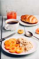 Porridge with apricot, coffee, glass of juice and croissant