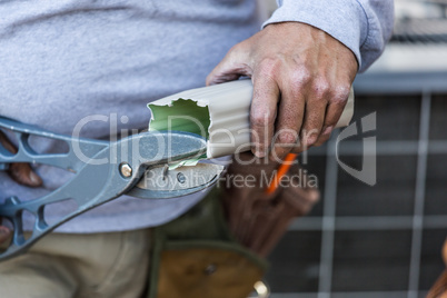 Worker Cutting Aluminum Rain Gutter With Heavy Shears