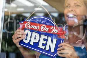 Happy Female Store Owner Turning Open Sign in Window