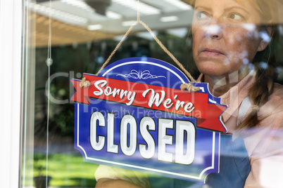 Sad Female Store Owner Turning Sign to Closed in Window