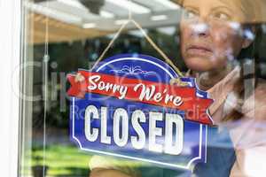 Sad Female Store Owner Turning Sign to Closed in Window